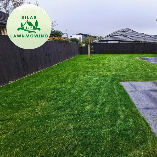 Freshly mowed back lawn beside a black fence and paved patio in Glen Eden, Auckland
