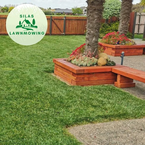 Tidy lawn beside a raised timber garden bed and palm in West Auckland