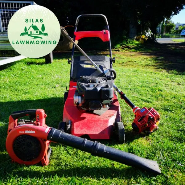 Lawn mower, blower and line trimmer set out on a lawn ready for edging and tidying